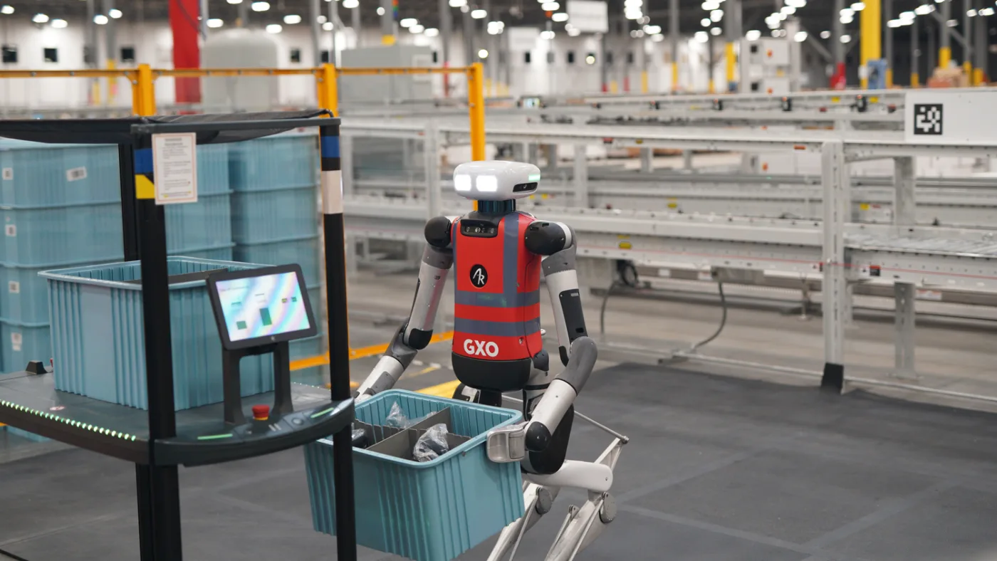 Agility Robotics Digit carrying a gray tote inside a GXO warehouse
