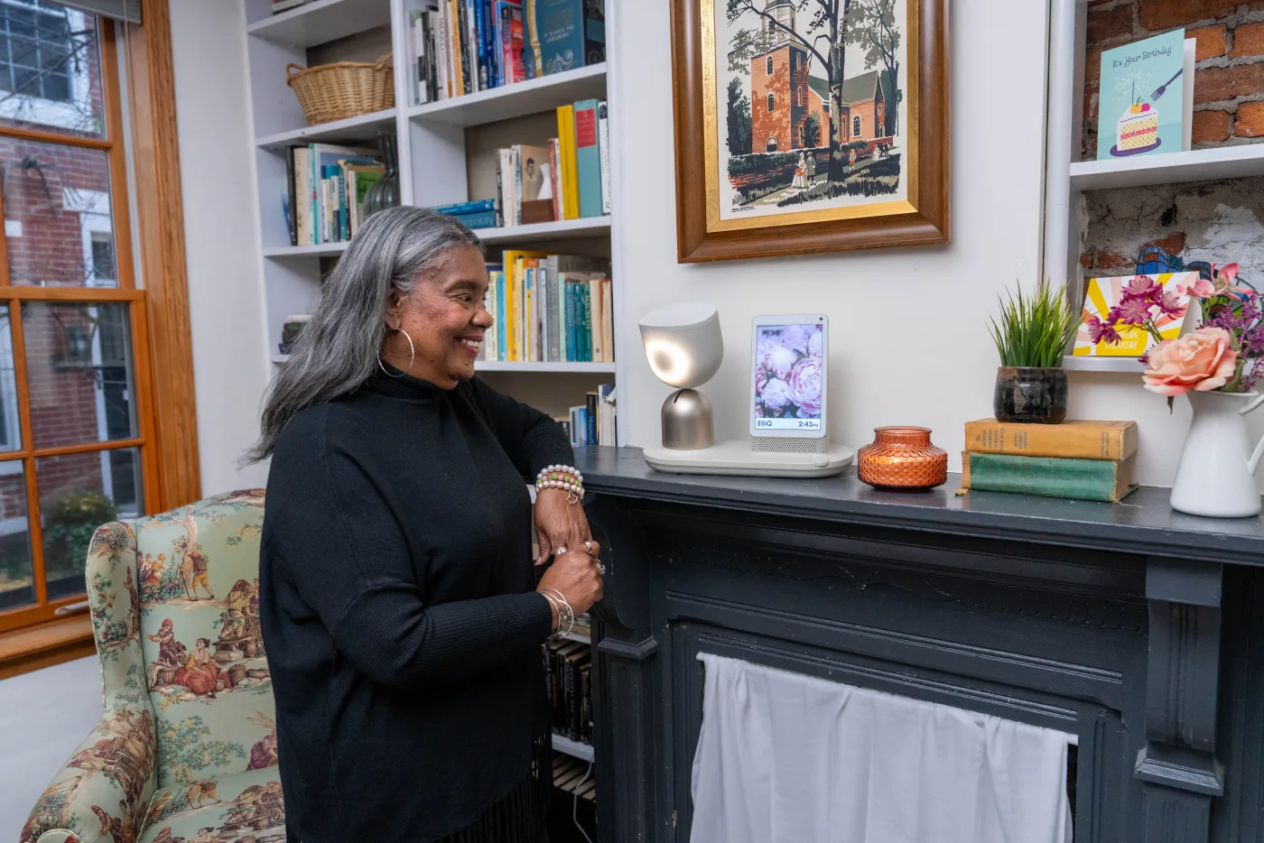 An older adult seated at home talking with the ElliQ tabletop companion robot