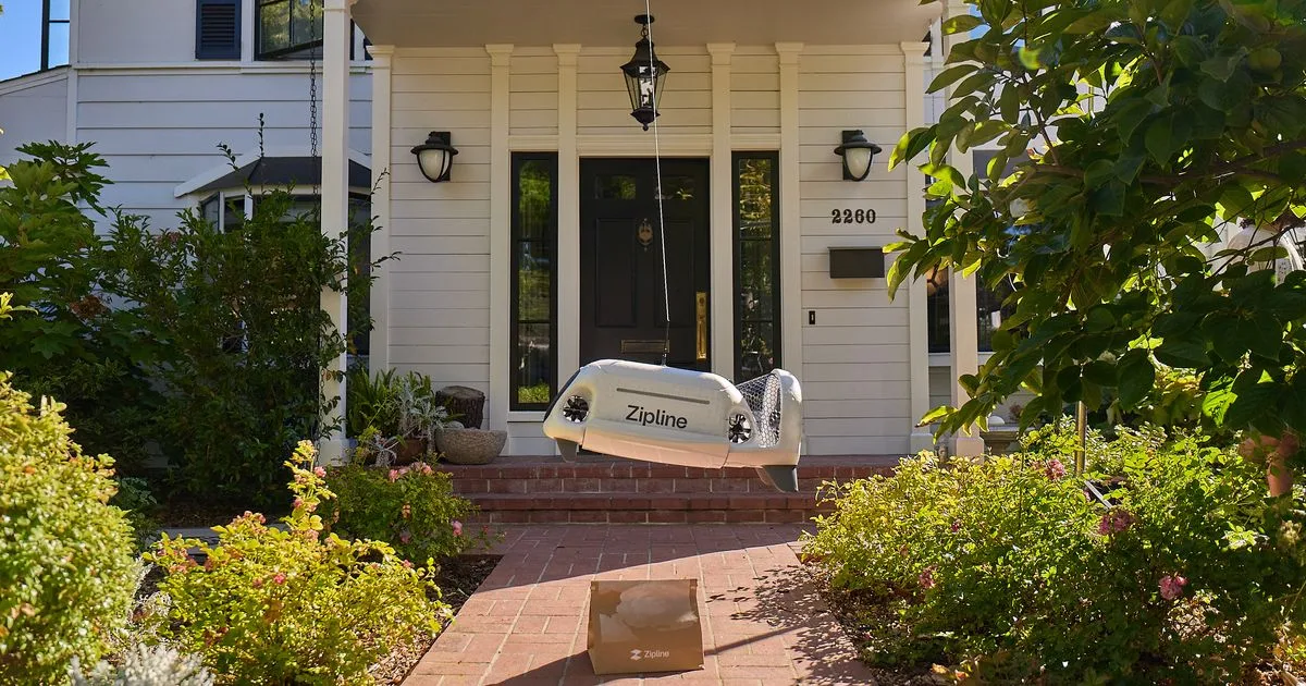 A Zipline autonomous delivery drone hovering above a package outside a house
